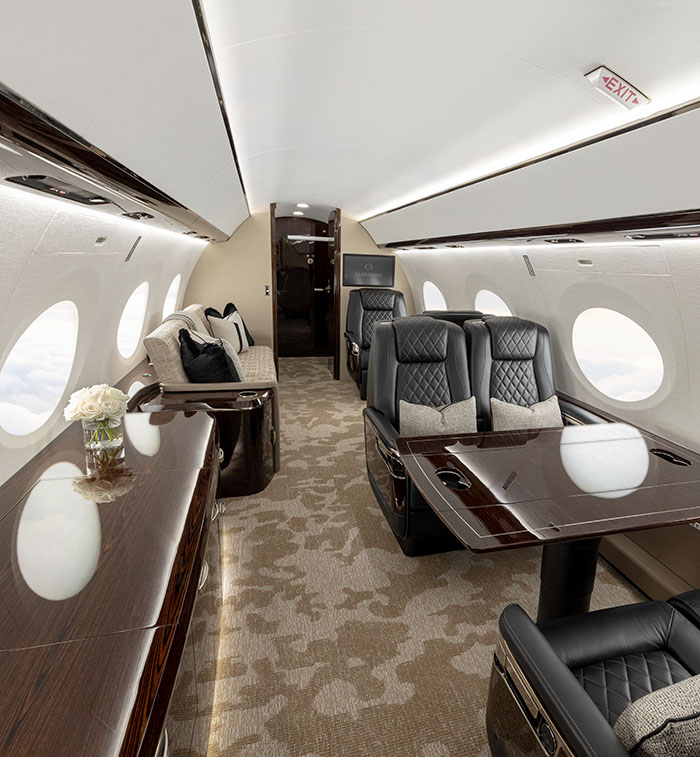 Gulfstream G800 main cabin with a large monitor playing a video and a divan on the left and club seating around a table on the right