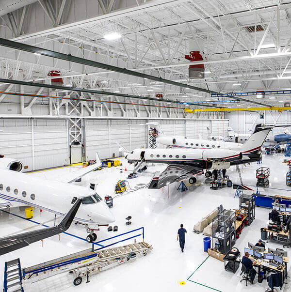 Gulfstream Customer Support employees work on aircraft in a service hangar.