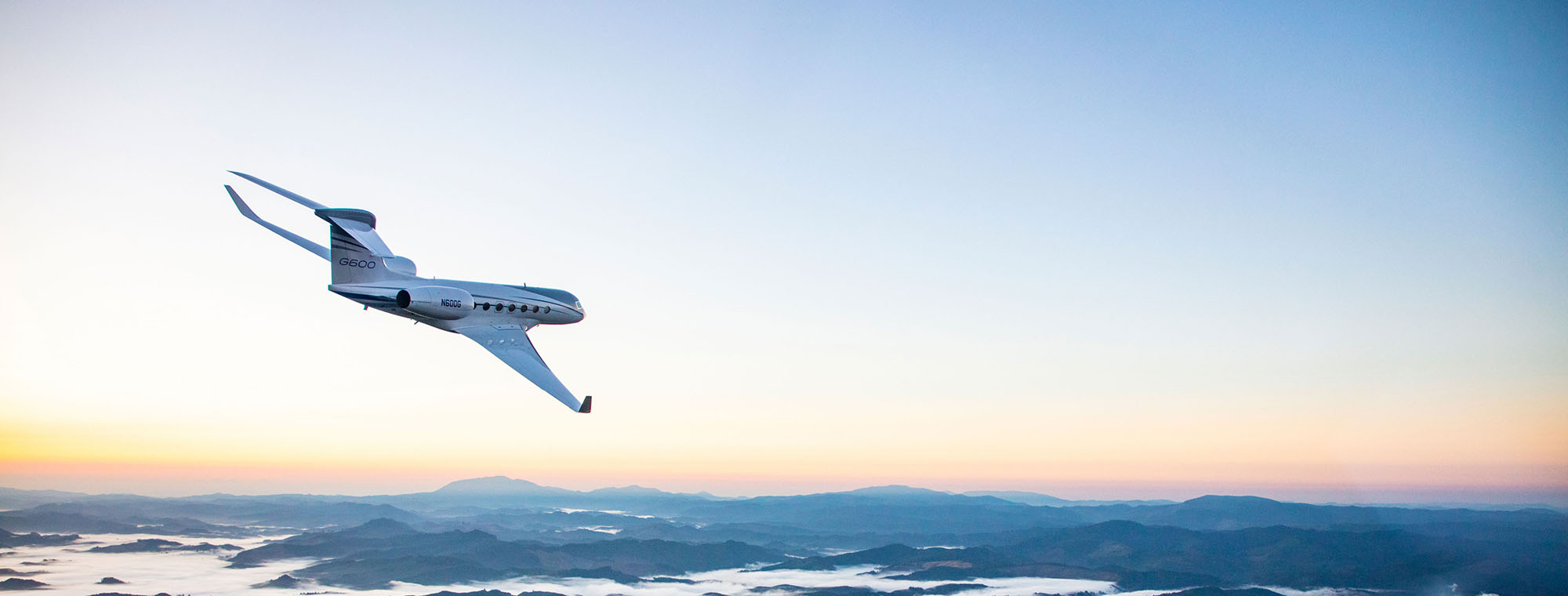 A Gulfsream G600 flies banks into a turn in a cloudless sky.